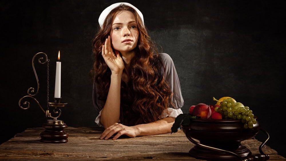 Hope. Creative portrait of young beautiful redhead girl in image of medieval person in renaissance style dress isolated on dark background. Comparison of eras, beauty, history, art, creativity.