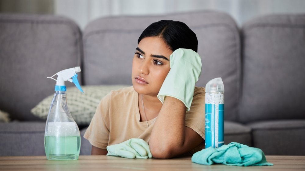 House, cleaning and bored woman thinking, tired and annoyed with household task, sad and frustrated. Lazy, cleaner and Indian girl contemplating, daydream and distracted from bacteria or dust cleanup