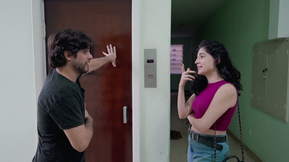 Couple conversing while waiting for elevator at older building. Man and woman going out in conversation while standing at hallway