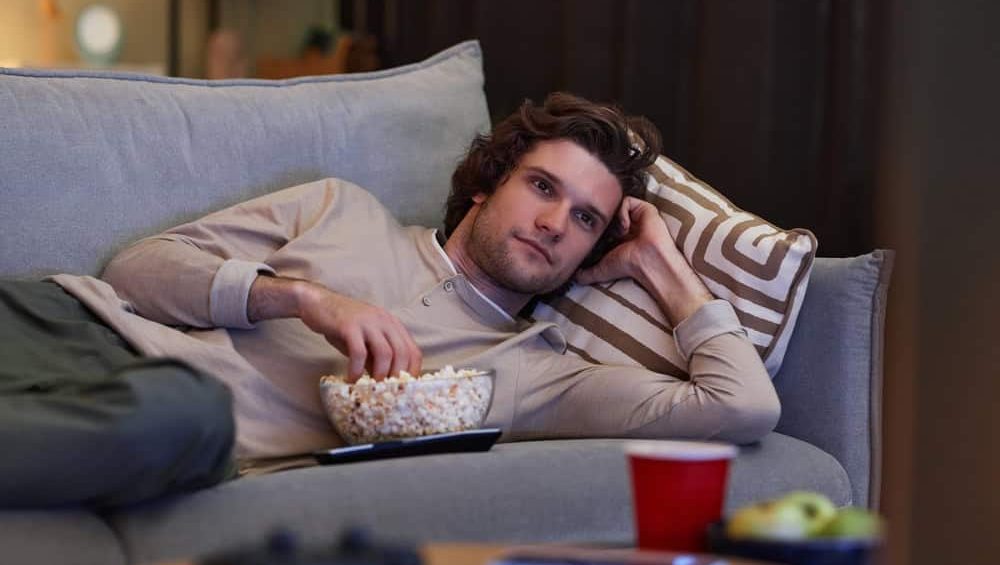 Portrait,Of,Young,Man,Watching,Tv,At,Home,And,Eating