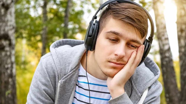 Young Man in Headphones listen to the Music in the Forest