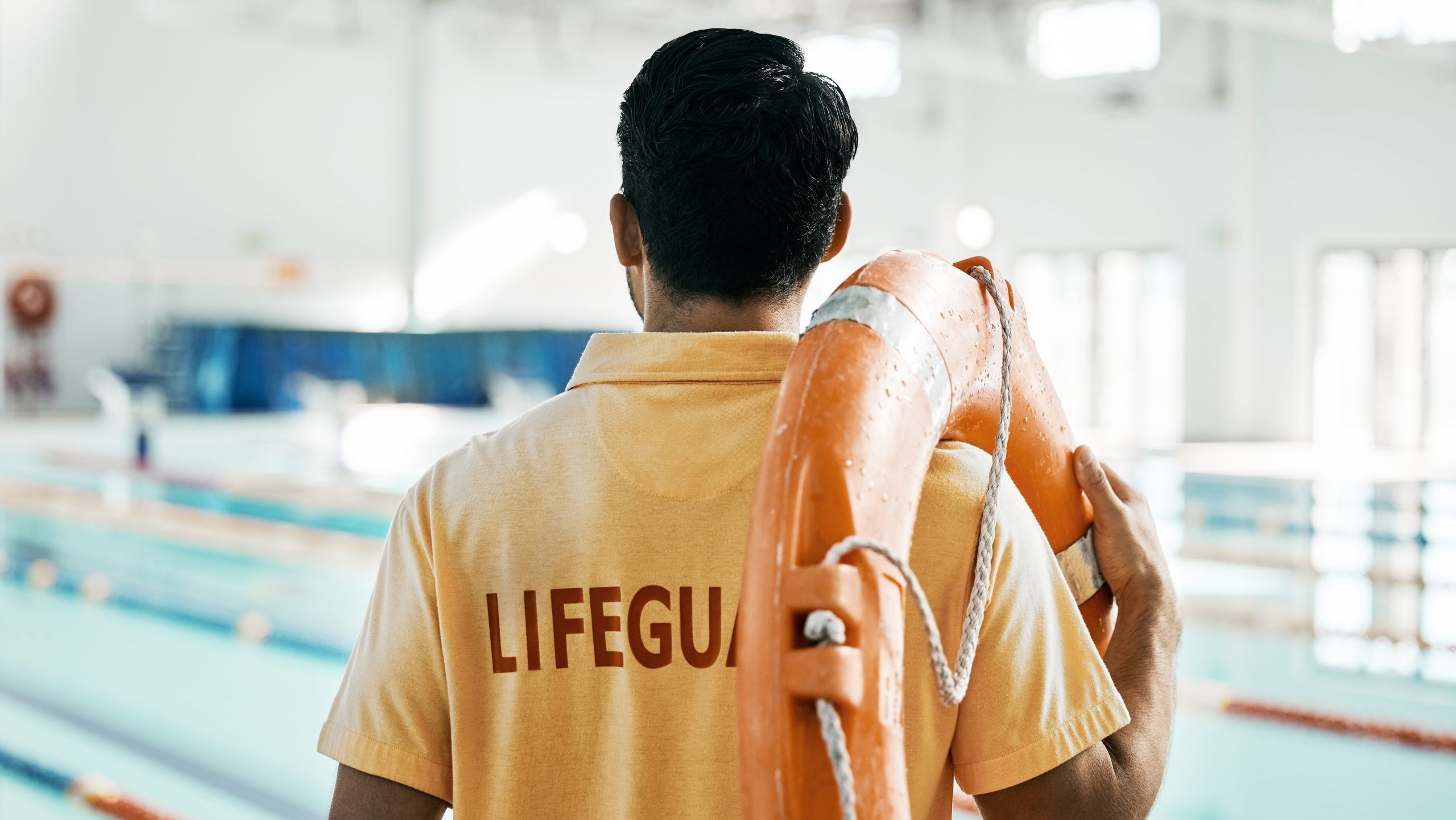 Lifeguard, back and person with swimming, pool or safety lifebuoy for rescue support, help or life saving. Surveillance attention, equipment and expert for protection, security or medical emergency