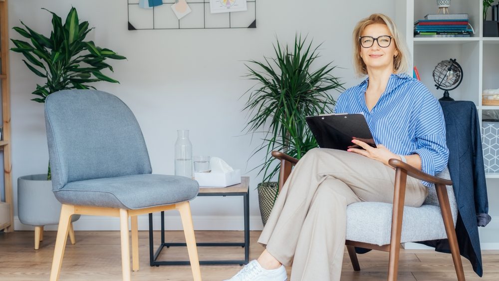 Professional Psychotherapy. Successful female Psychologist Smiling To Camera Sitting On armchair In Office. Mature 50s middle-age professional portrait of teacher, coach, mentor, therapist, counselor