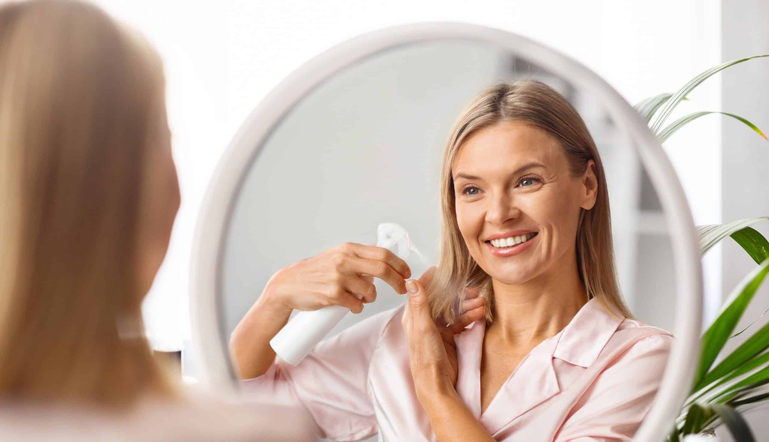 Haircare.,Smiling,Middle,Aged,Woman,Applying,Hair,Spray,While,Standing
