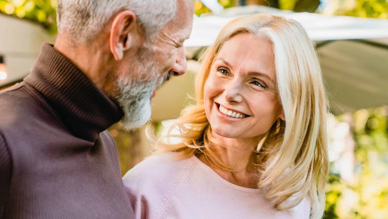 Cheerful senior couple looking at each other with passion and love in the park. Middle-aged spouses having romantic date outdoors outside. Quality time - love language
