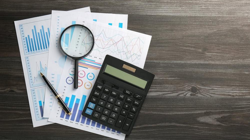 Accounting documents, magnifying glass, calculator and pen on wooden table, top view. Space for text