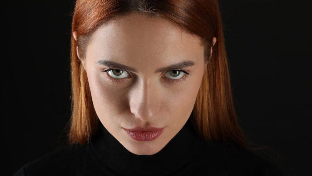 Evil eye. Young woman with scary eyes on black background