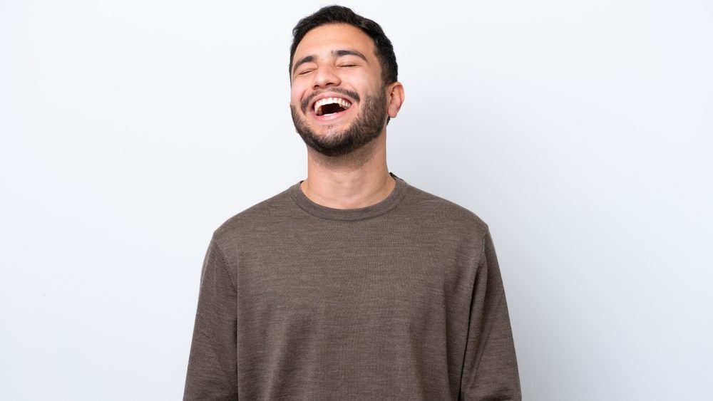 Young Brazilian man isolated on white background laughing