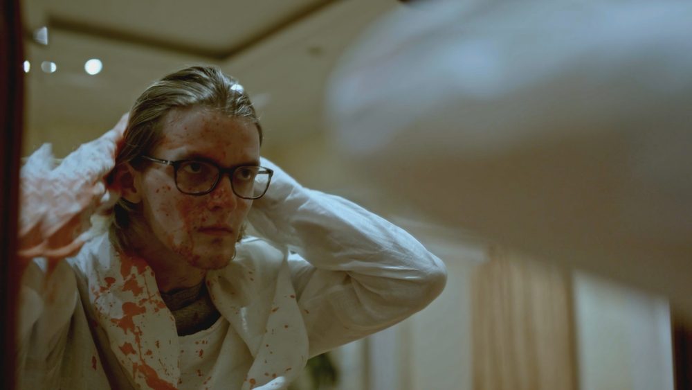 Man is covered in blood after murder. Stock. Young man is covered in blood after murder in apartment. Man stained with blood is in shock after murder