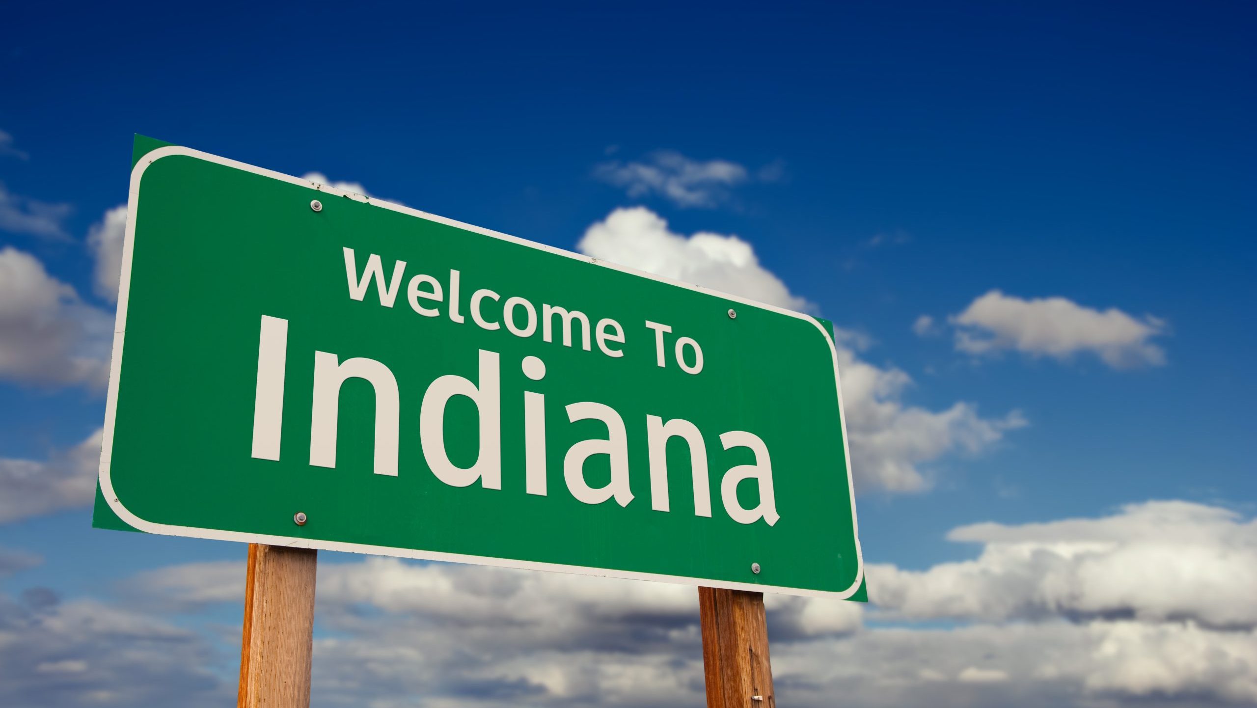 Welcome To Indiana Green Road Sign Over Blue Sky with Some Clouds.