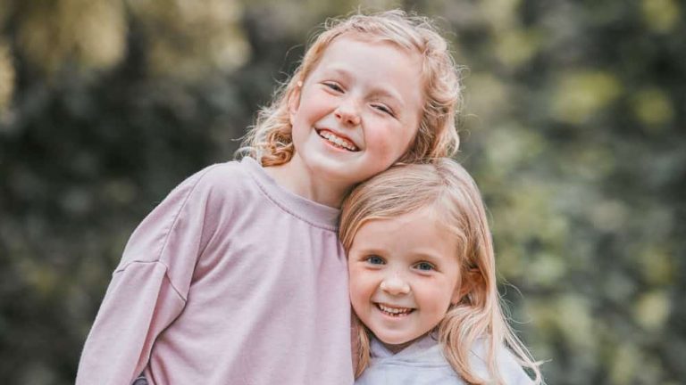 Outdoor, smile and siblings in portrait with hug, playful and bonding together with childhood games in park. Garden, children or girls with embrace for connection, development and caring in backyard