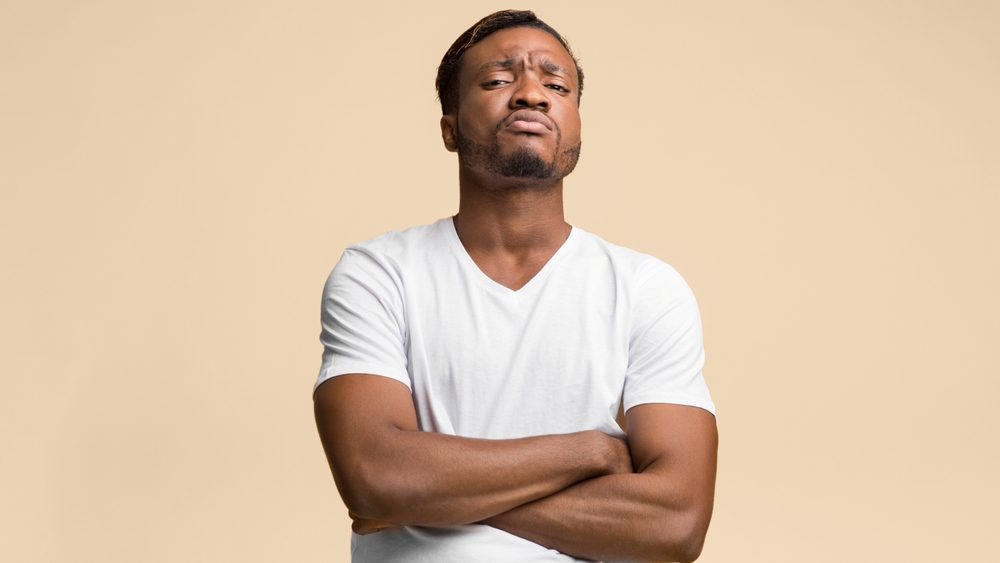 Serious Afro Man Standing Crossing Hands Looking At Camera Over Yellow Background. Studio Shot