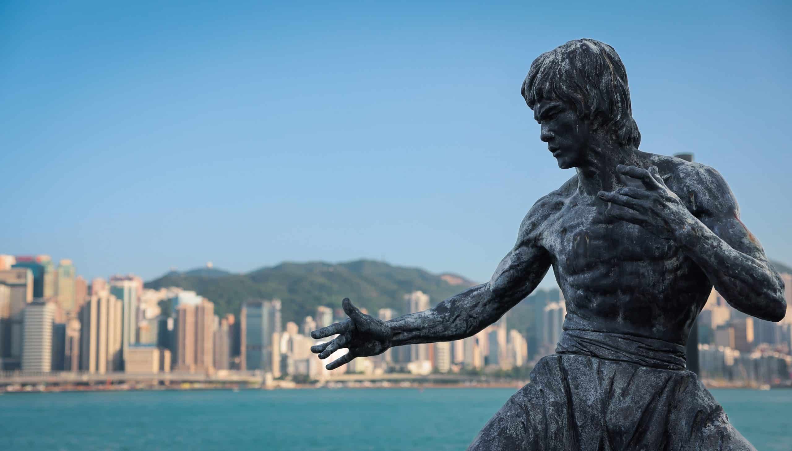 Hong Kong City, Hong Kong - April 15, 2024: Bruce Lee statue stands proudly on the Hong Kong waterfront against a backdrop of the city skyline