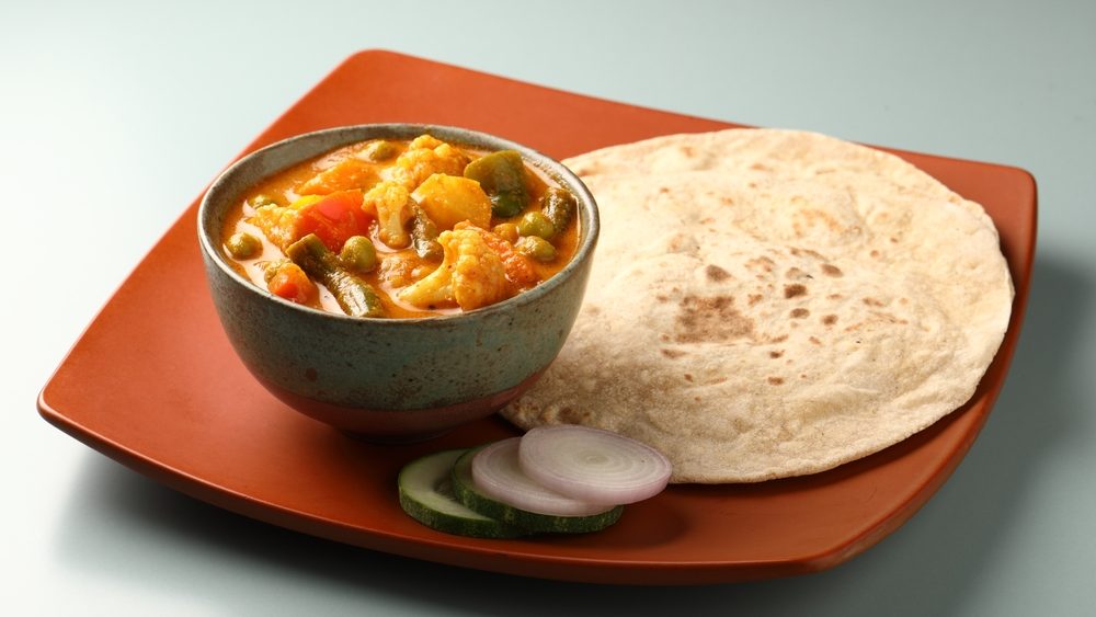 Mix vegetable curry - Indian main course recipe contains Carrots, cauliflower, green peas and beans and served in ceramic ware with Chapati ,Indian flat bread , roti