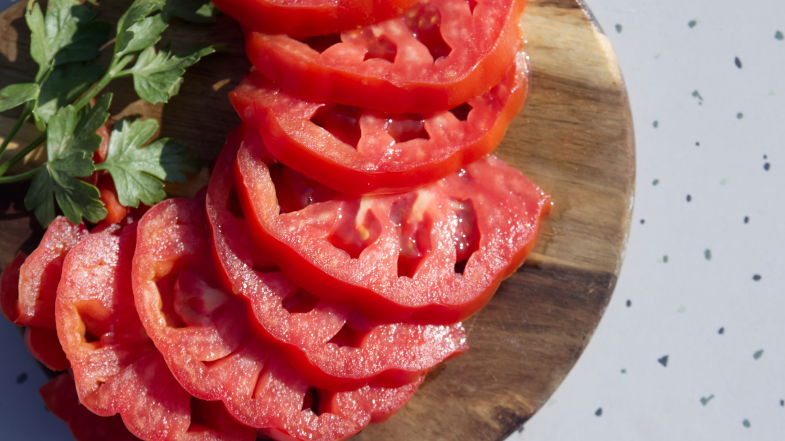 Sliced ​​tomatoes on wooden stand on table