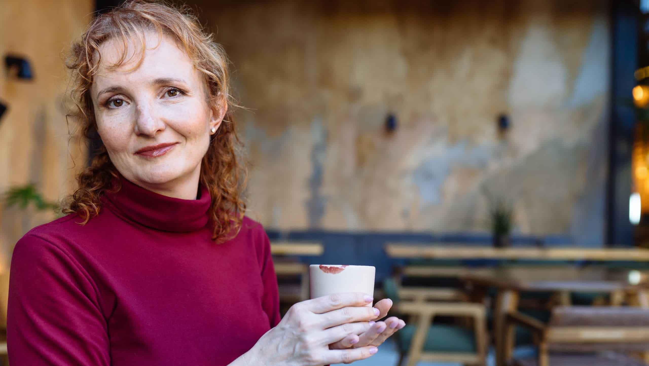 Middle-aged,Caucasian,Woman,With,Red,Hair,Holds,Mug,With,Lipstick