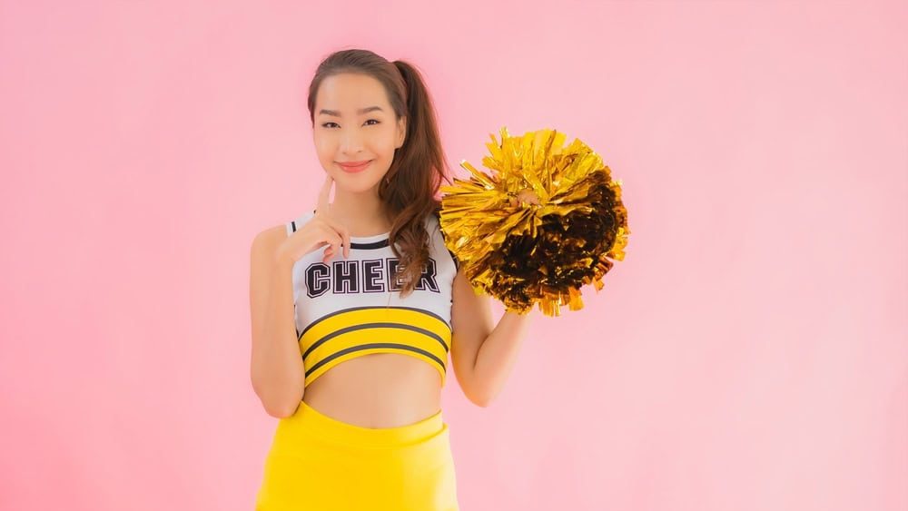 Portrait beautiful young asian woman cheerleader on pink isolated background