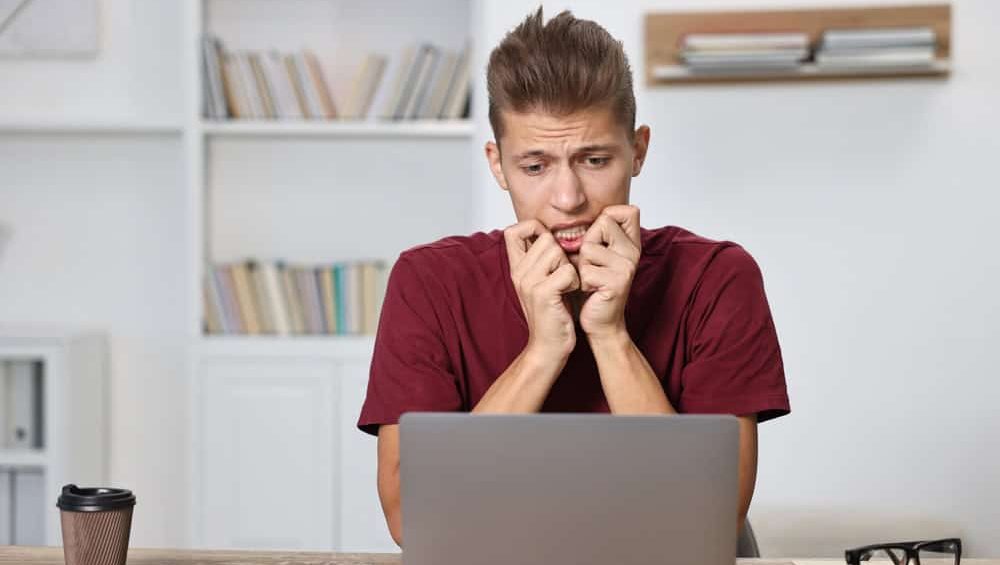 Tired student having stress before exam at table indoors