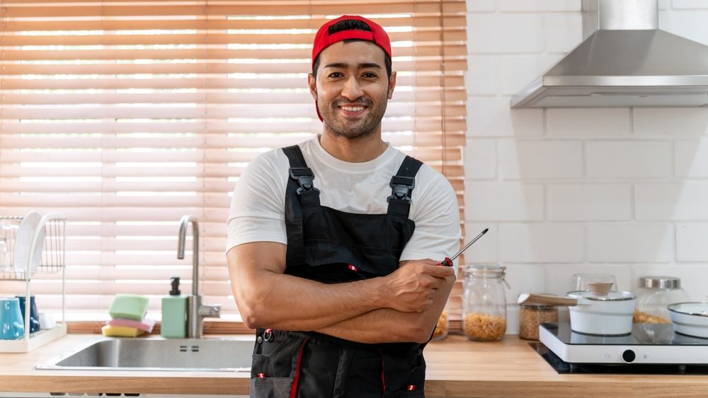 Portrait of Caucasian repair man installs new counter in kitchen at home. Attractive male worker feel happy and relax while working and maintenance service to customer's house then looking at camera.