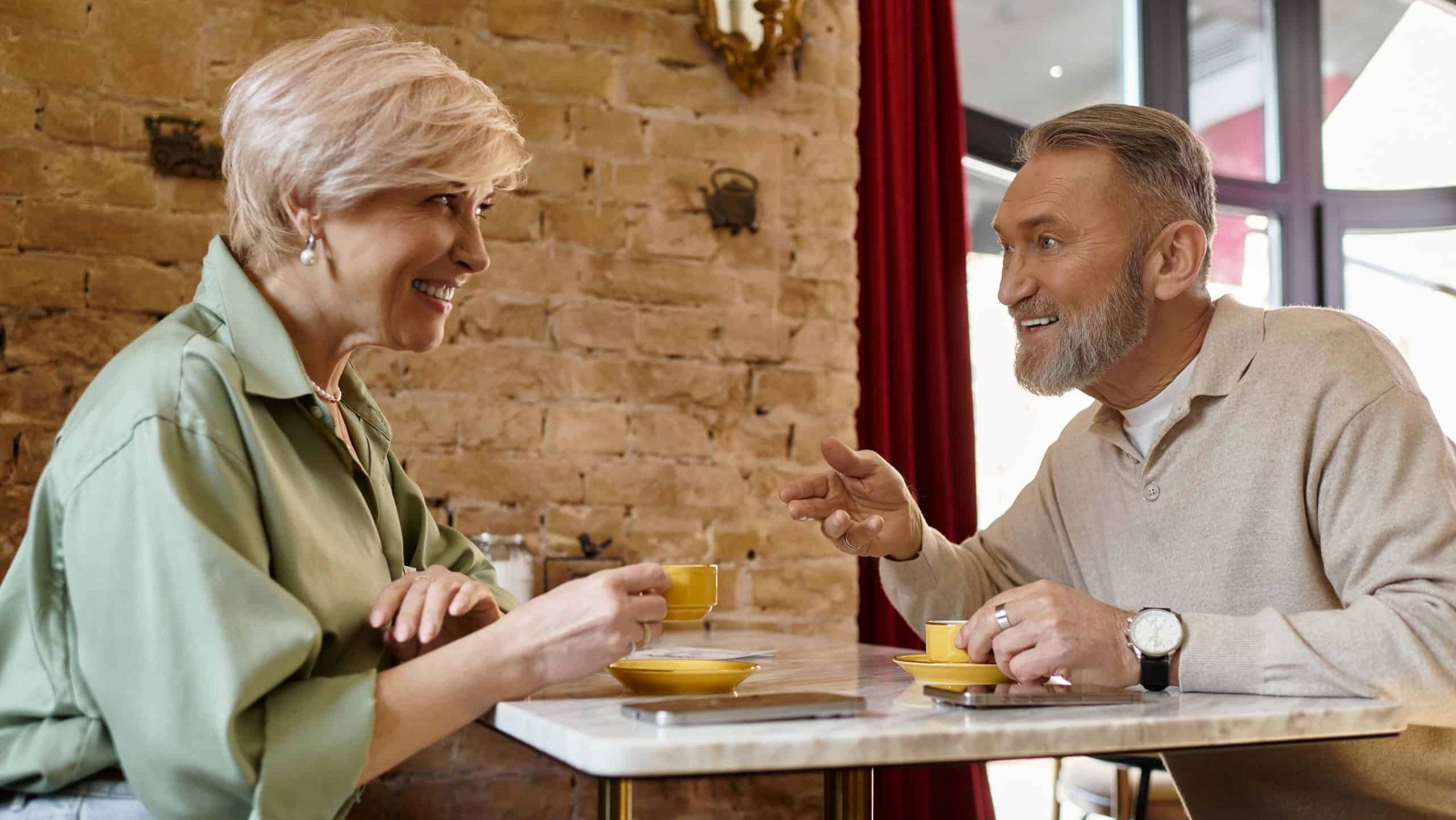 A middle aged couple shares smiles and laughter during a charming coffee date at a cozy cafe.