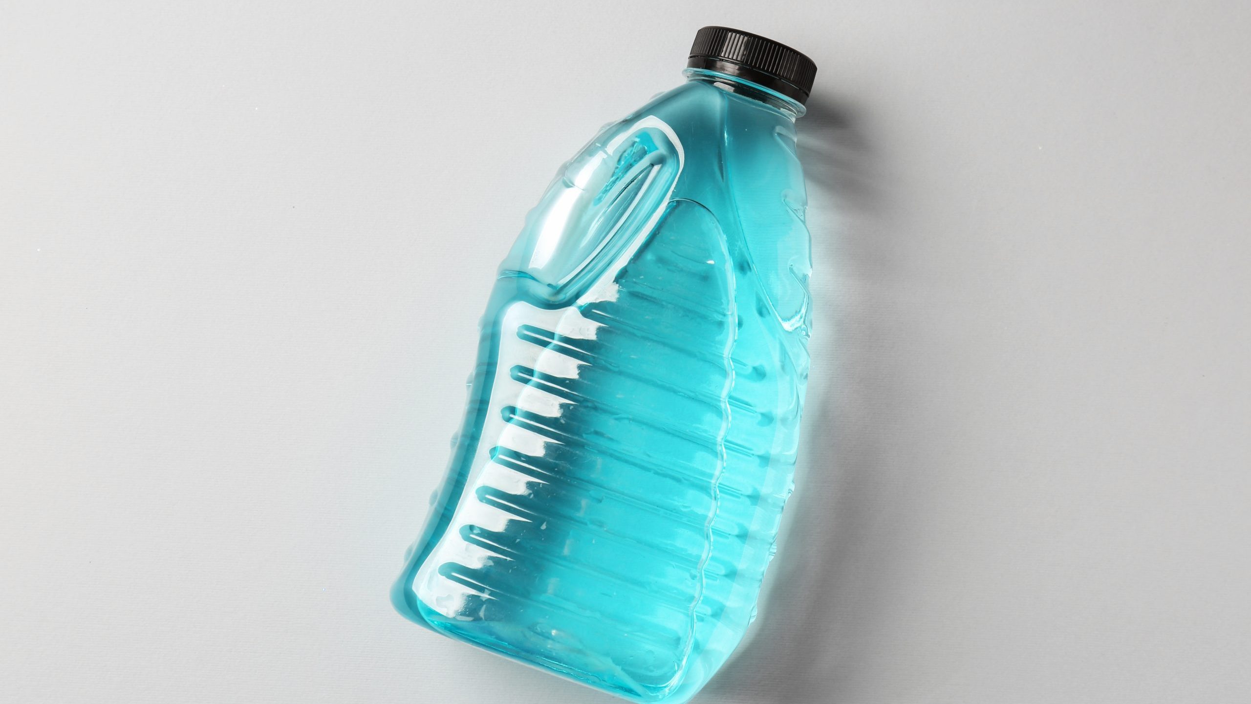 Antifreeze in plastic bottle on grey background, top view