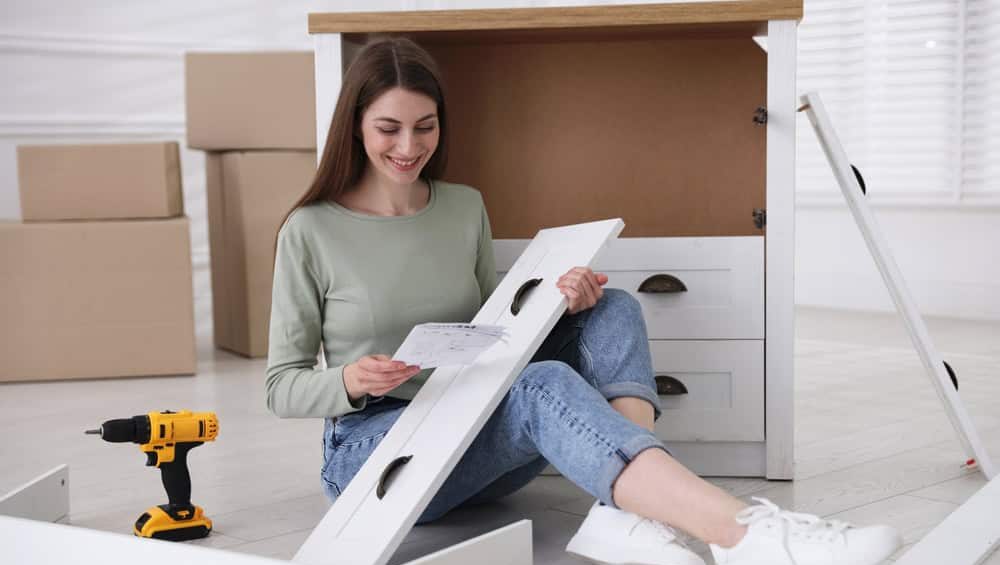 Smiling,Woman,With,Manual,Assembling,Furniture,On,Floor,At,Home