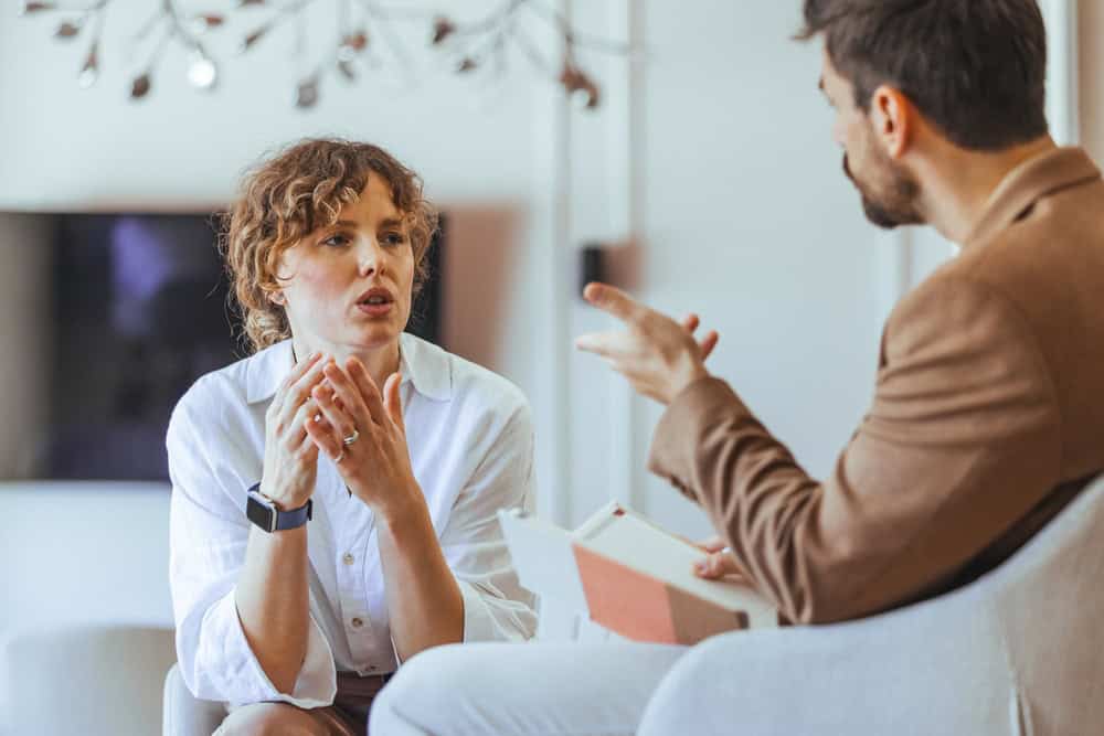 Two people are engaged in an intense dialogue in a well-lit, comfortable setting, emphasizing communication and collaboration.