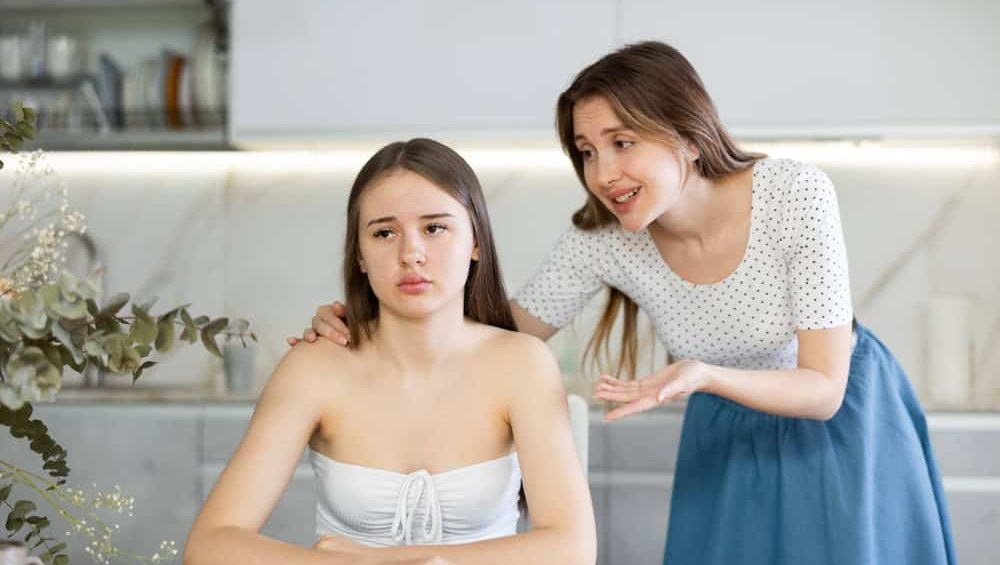 Two young women sisters in casual clothes quarrel in kitchen at home