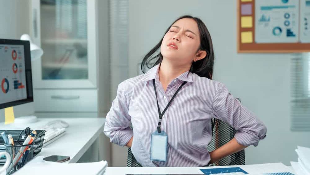 Young,Businesswoman,Gripping,Her,Lower,Back,,Displaying,A,Pained,Expression