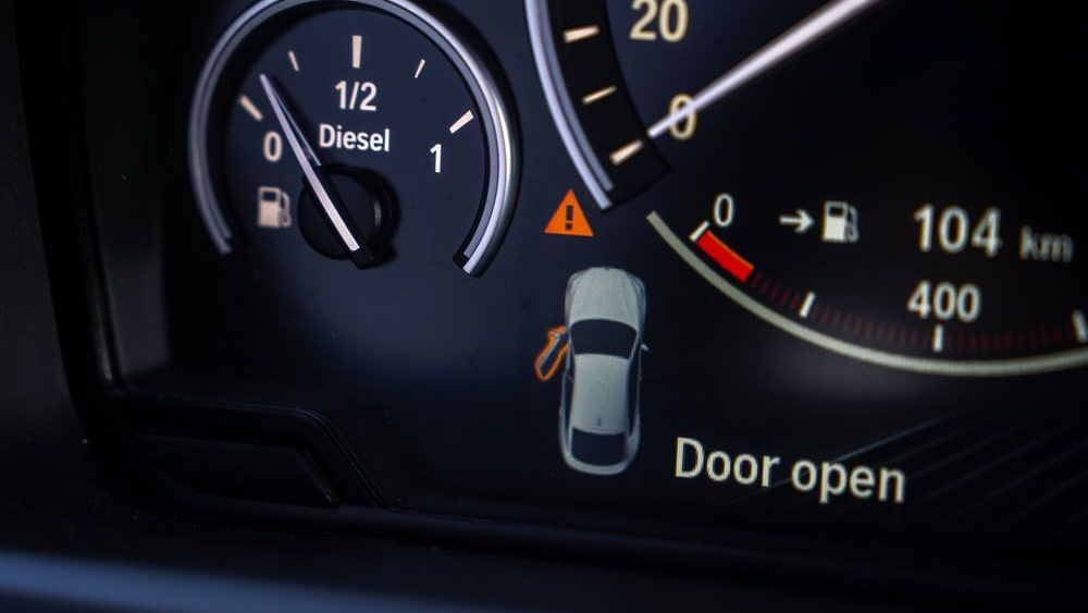 Riga, Latvia. May 5, 2025. Close up view of a BMW X6 instrument cluster showing a fuel gauge, speedometer, and digital display with a door open warning and 104 km range.