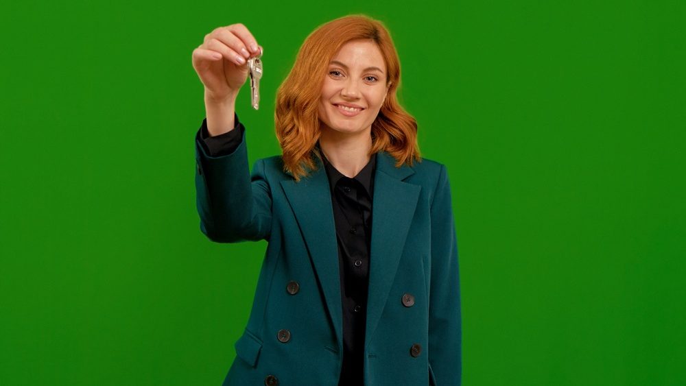 Woman raising keys boasting about new home on green screen isolate background. Rich lifestyle buying assets. Wealthy lifestyle concept.