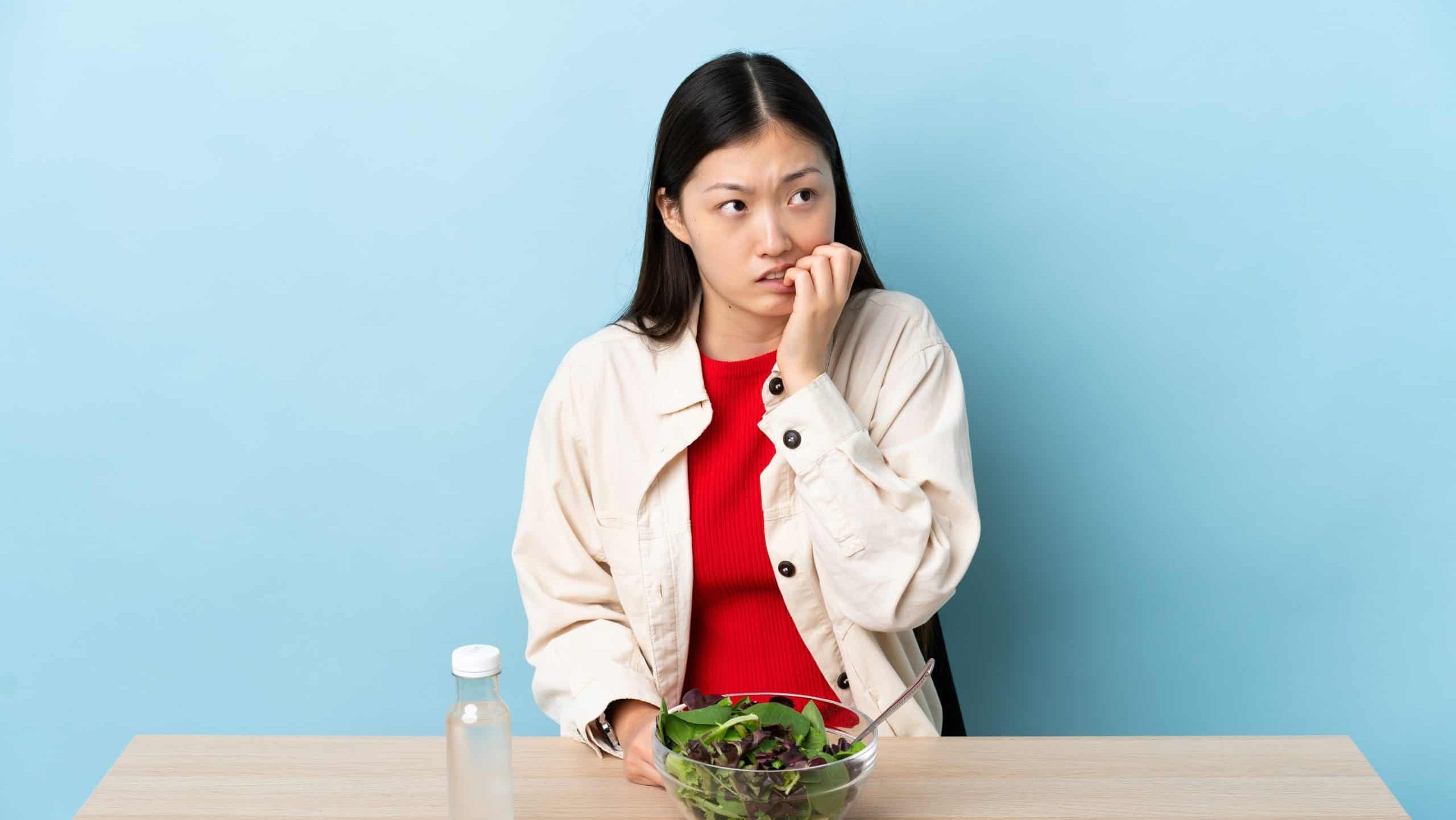 Young Chinese girl eating a salad is a little bit nervous