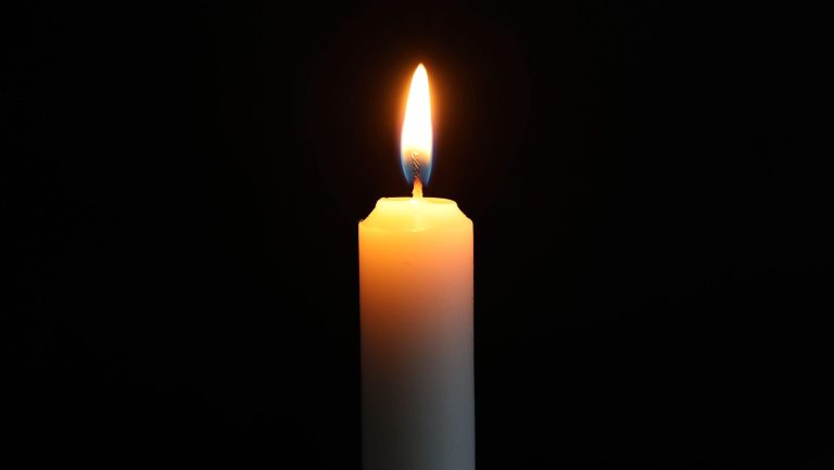 Burning candle on dark background, closeup