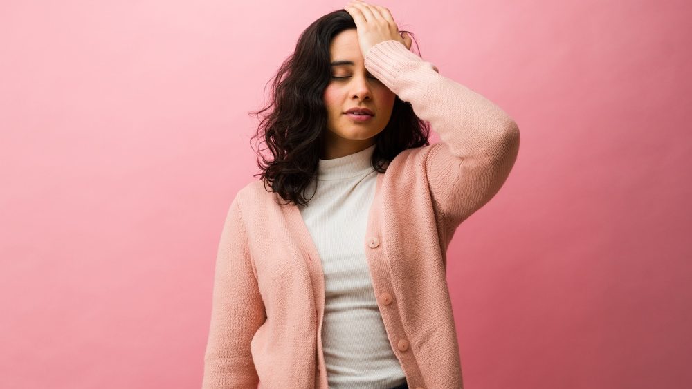 Frustrated young woman facepalming by making a mistake or forgetting something, expressing disappointment, stress, or regret