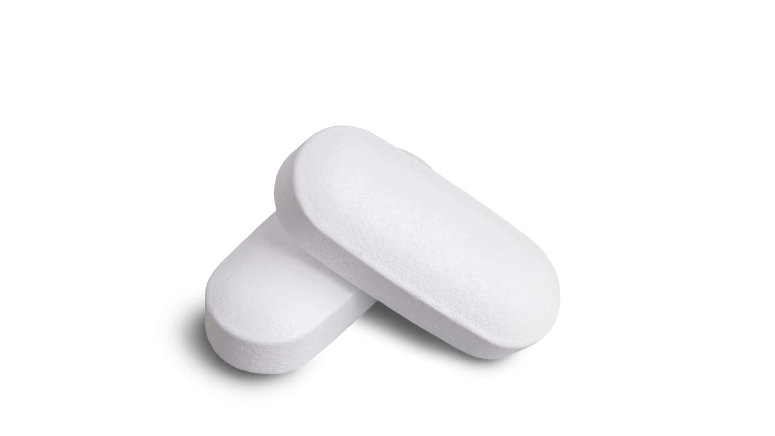 Macro of two white tablets, medicine pill capsules, supplement, vitamin isolated on white background. Medical and pharmaceutical concept for healthcare, treatment, medication, vitamins or supplements