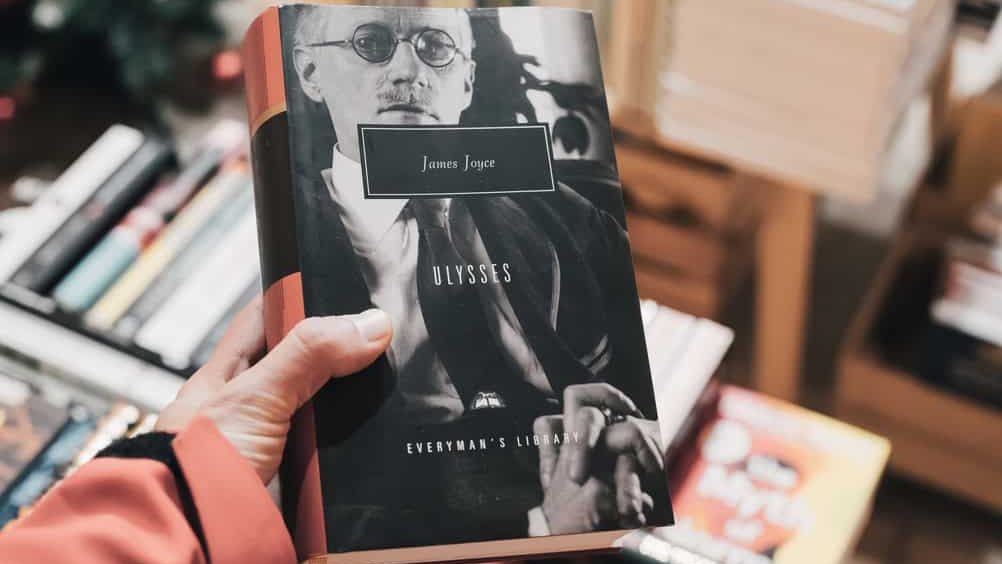 Hand holding a paperback copy of James Joyce's Ulysses from Everyman's Library, browsing literature in a bookshop