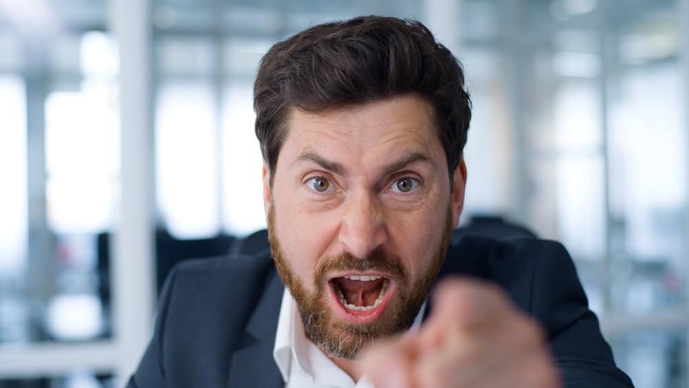 Close up negative angry Caucasian middle-aged business man talking with aggression looking at camera senior businessman mature male entrepreneur talk furious work problem working video call in office