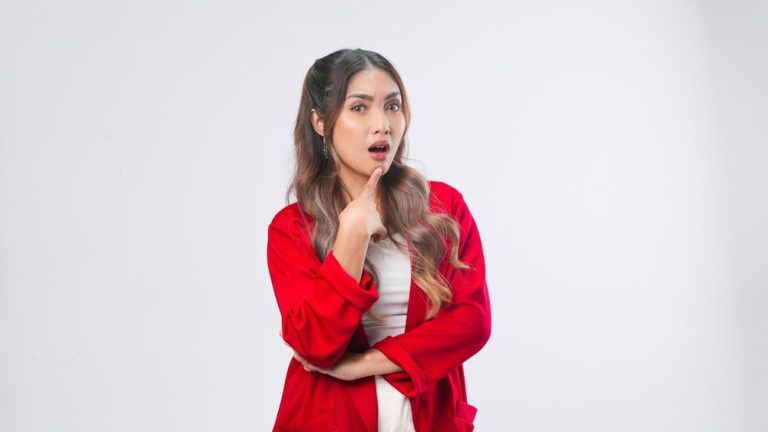 Confused young Asian woman in a red jacket is thinking hard to find idea, isolated by white background.