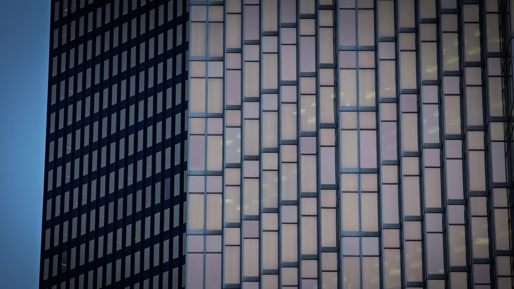 Abstract close view of skyscraper windows and office tower facades in a North American downtown, showing glass patterns, corporate architecture and a business background.