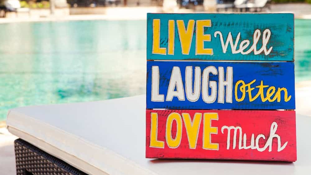 Inspirational Motivational Life Quote wooden board Live well Laugh often Love much on summer, tropical swimming pool background Copy space