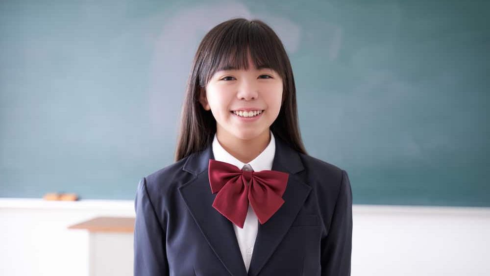 A Japanese junior high school girl stands in the classroom with a smile