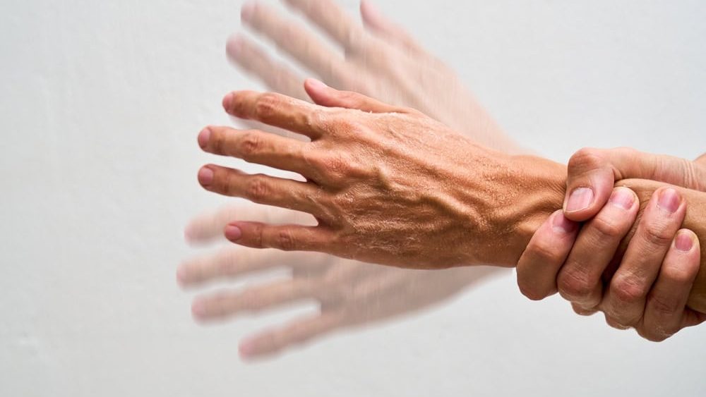 Trembling hand holding glass concept parkinson.