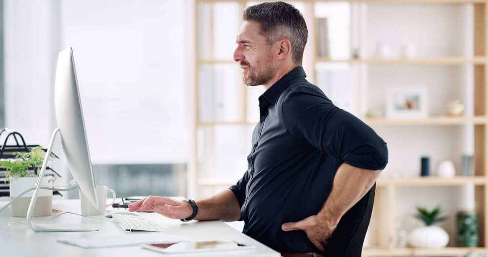 Business, man and computer with back pain in office from muscle injury, bad posture or inflammation. Pressure, mature person or tech with uncomfortable ache from long hours, overworked or discomfort