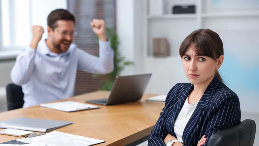Woman feeling jealous of her colleague's success in office, selective focus