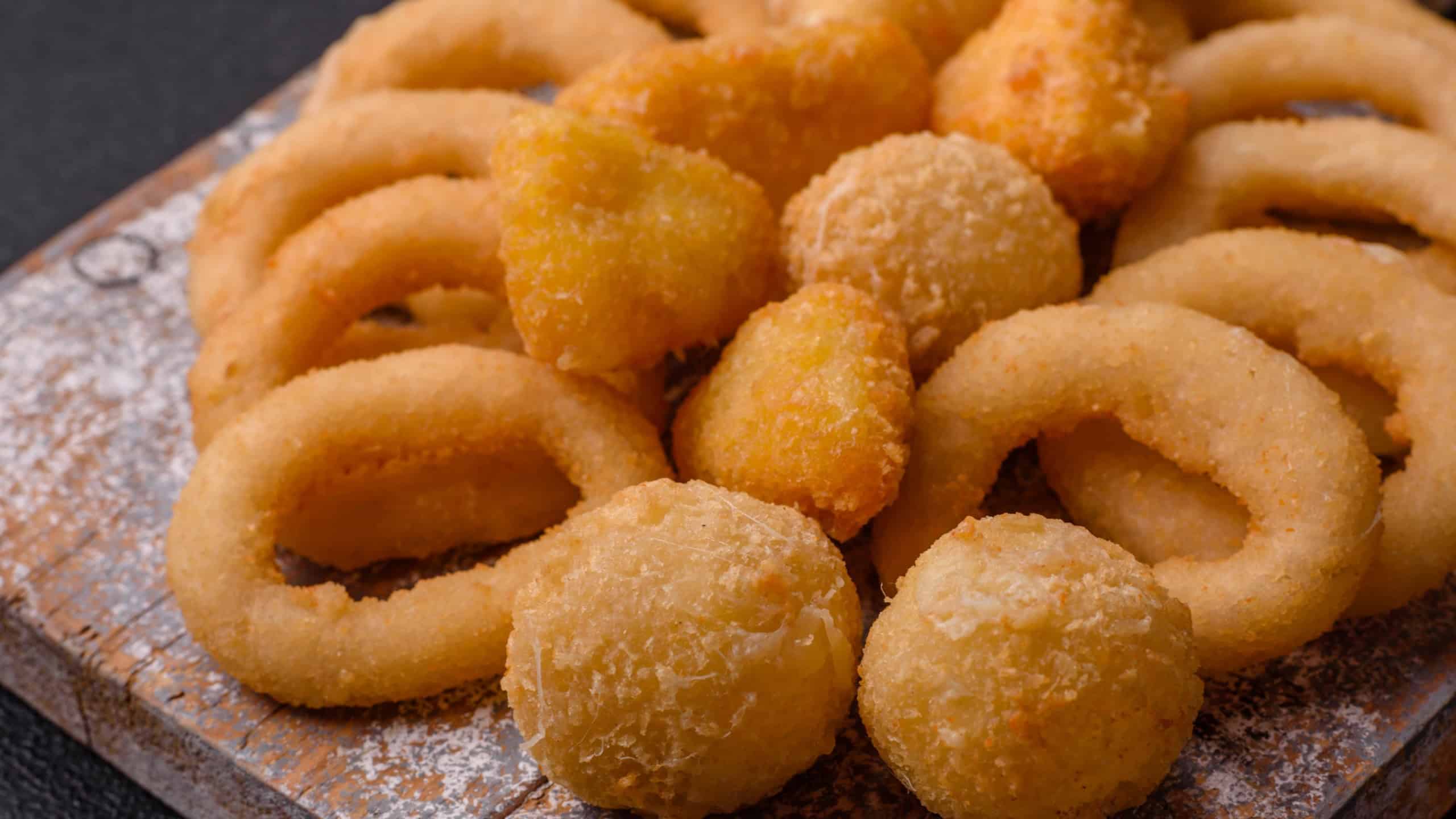 Food, chicken nuggets, onion rings and cheese balls on dark background. Fast food, unhealthy lifestyle