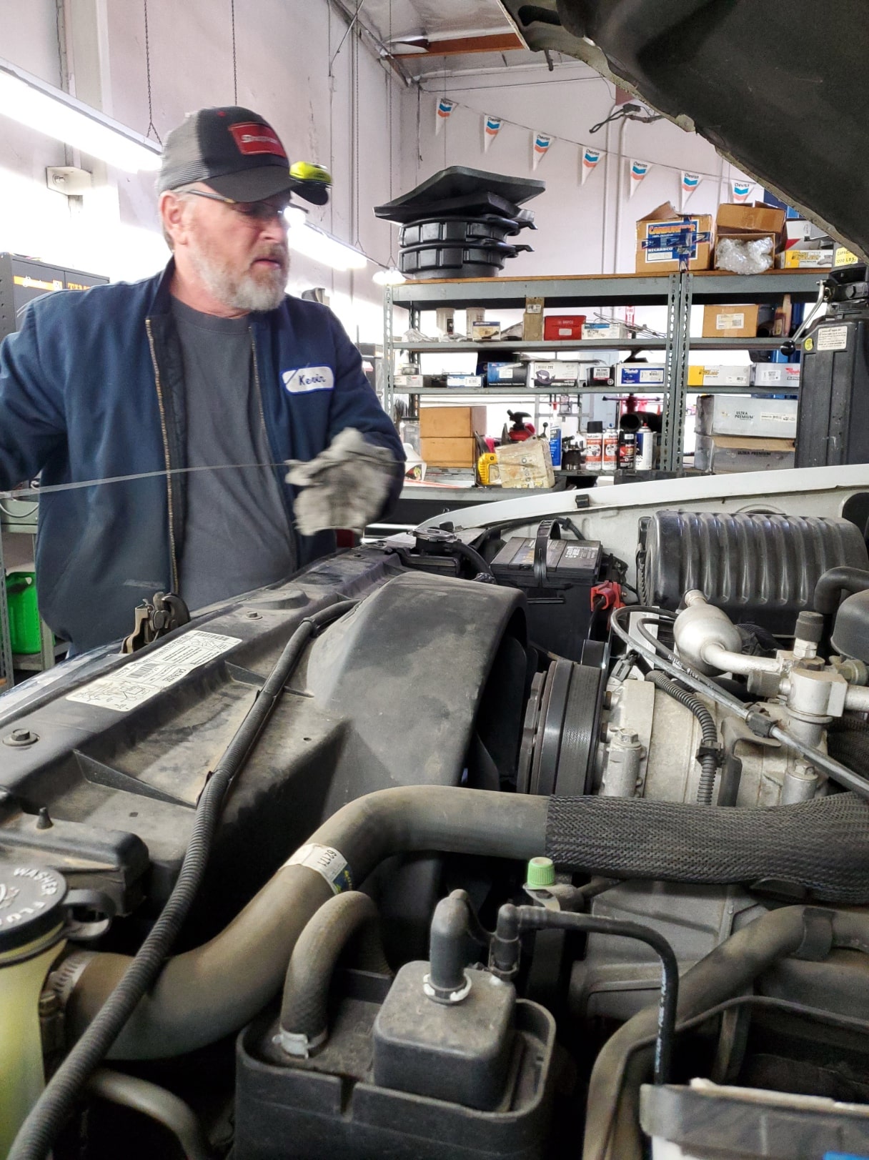 Auto repair technician inspecting engine components.