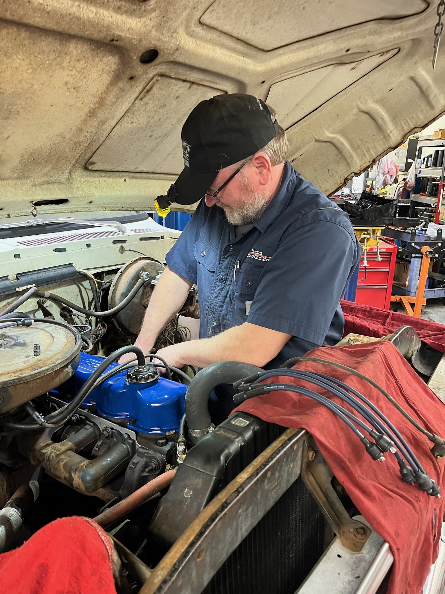 Engine repair at Auburn Service Center, professional mechanic working on vehicle engine.