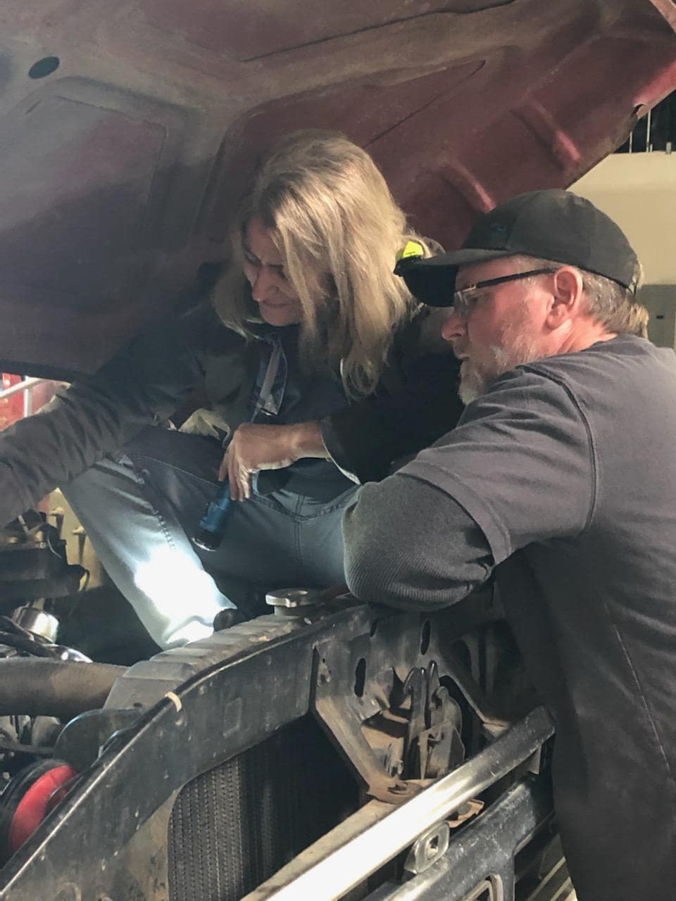 Auto repair technicians inspecting vehicle engine under the hood.