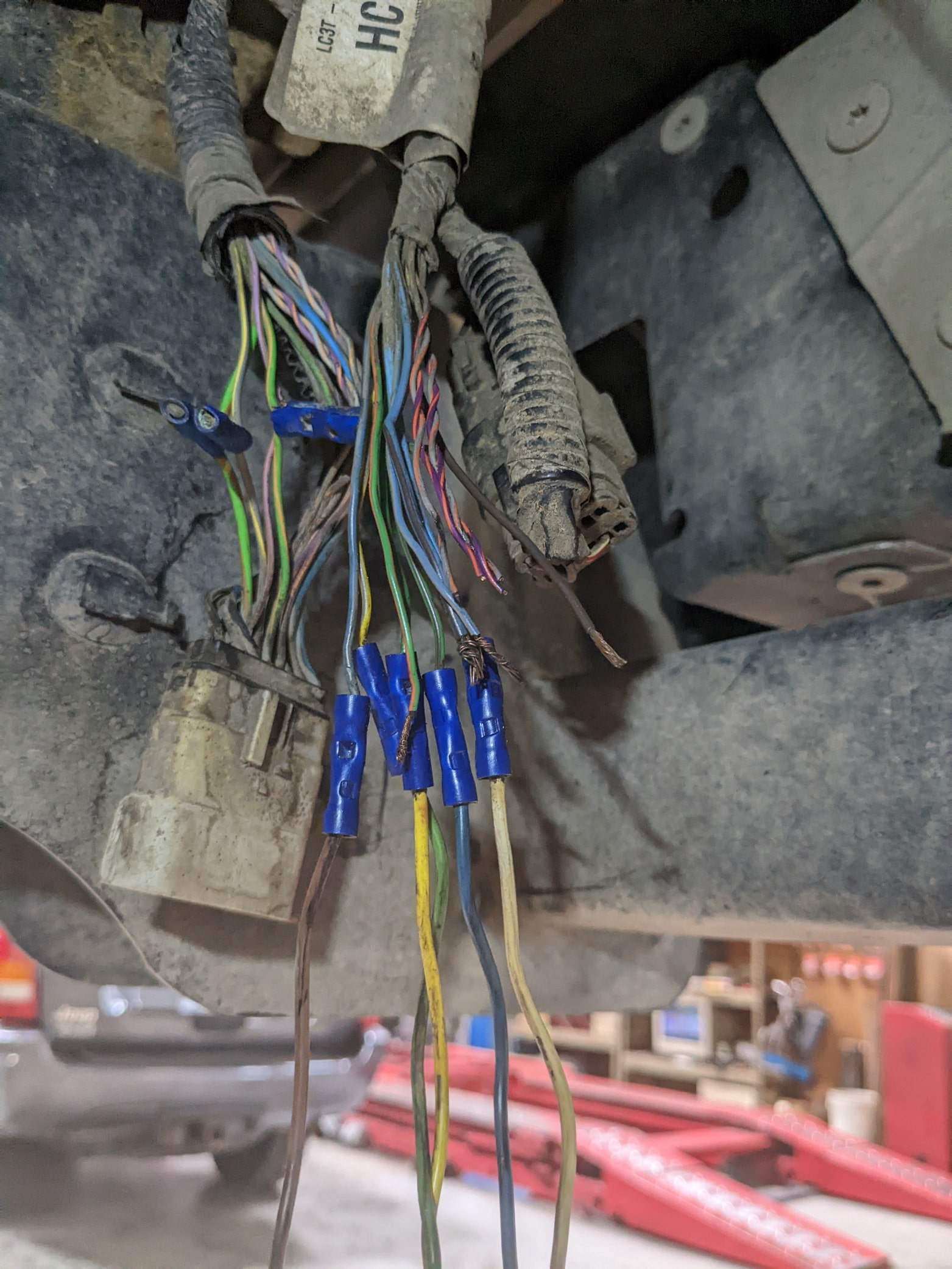 Wiring harness with multiple colorful wires and connectors under a vehicle.