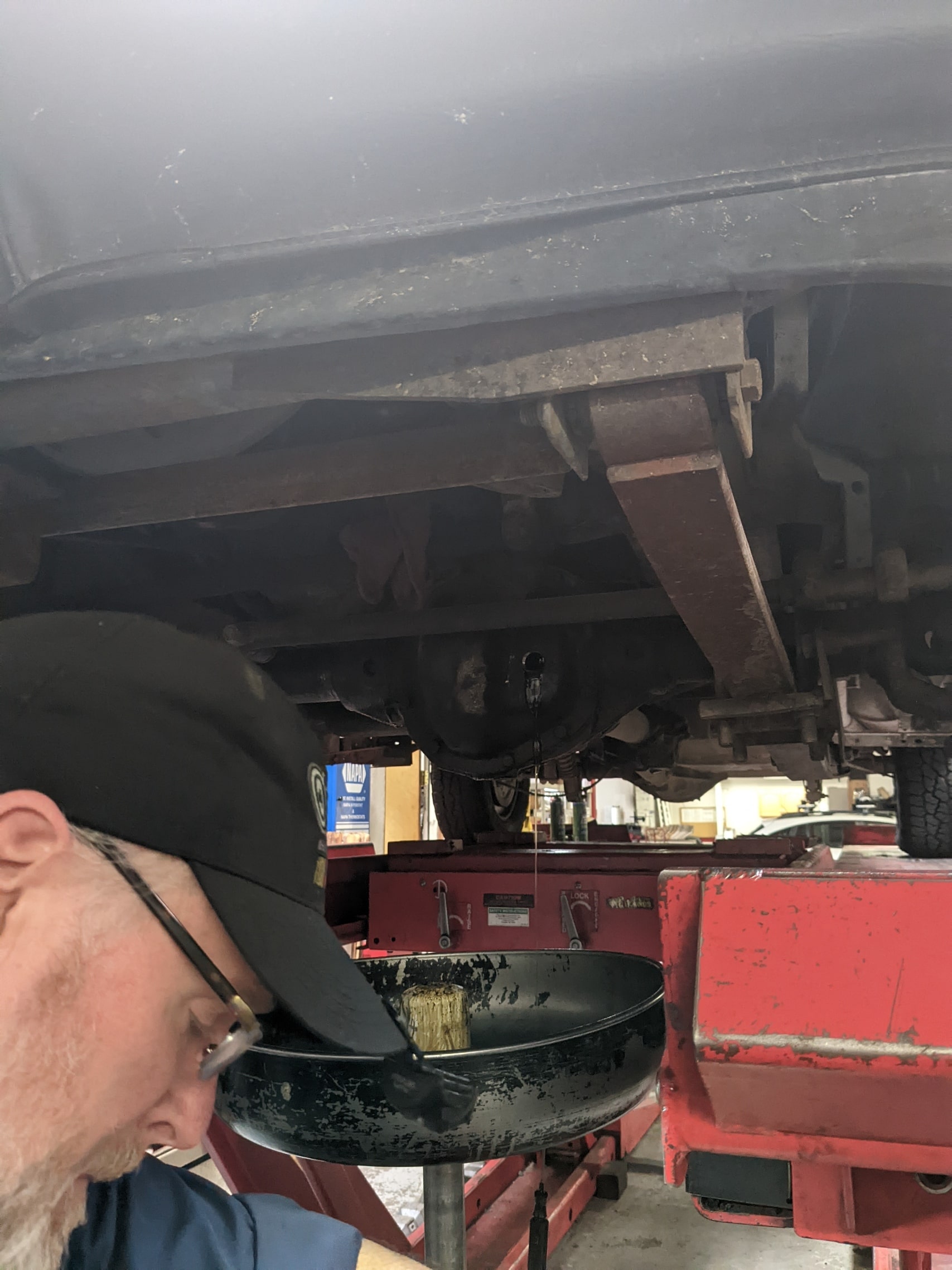 Mechanic performing oil change under vehicle at Auburn Service Center.